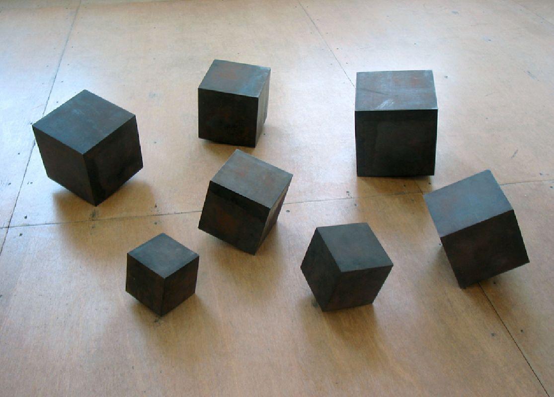 Joachim Bandau, Zeven Kubusbeelden, 1998, staal, met een rad of wals recht of schuin gekanteld; 12 x 12 x 12 cm., 14 x 14 x 14 cm., 17 x 17 x 17 cm., 18 x 18 x 18 cm., 20 x 20 x 20 cm., 21 x 21 x 21 cm., 24 x 24 x 24 cm. Deze gepuntlaste stalen objecten vormen een groep van autonome werken, die op de grond of op een sokkel van 1.50 m. hoog worden geplaatst.
PHŒBUS•Rotterdam