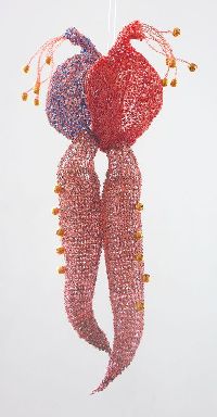 Regula Maria Müller,' ...op zijn hart...', 2008, glas, koper en glaskralen gehaakt, ca. h 0.34 x ø 0.06 m. (met de vorm van het hart in twee delen (gehaakt roodkoperdraad, met glaskralen in rood en blauw), waaraan twee glazen vormen van tongen, die ook in roodkoperdaad met glaskralen zijn gehuld. Het werk refereert aan gezegdes: 'het hart op de tong hebben', 'lang van tong zijn', 'met een dubbele tong spreken'.
PHŒBUS•Rotterdam